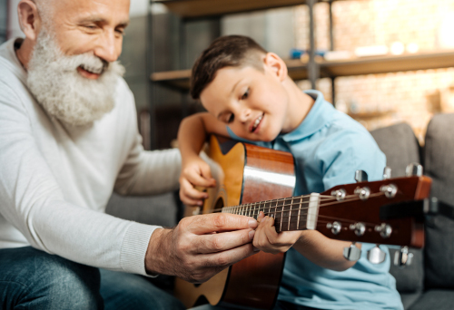 Boy learns guitar with instructor