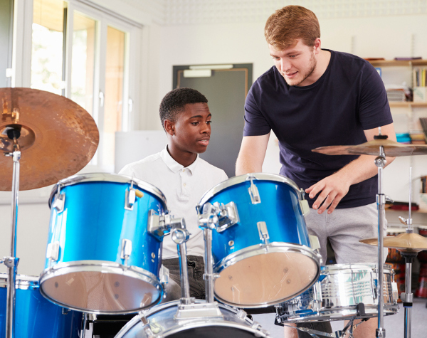 Drum teacher assists student Teacher instructs student on drums